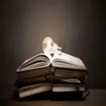Stack of books with glowing lightbulb symbolizing knowledge sharing and insight